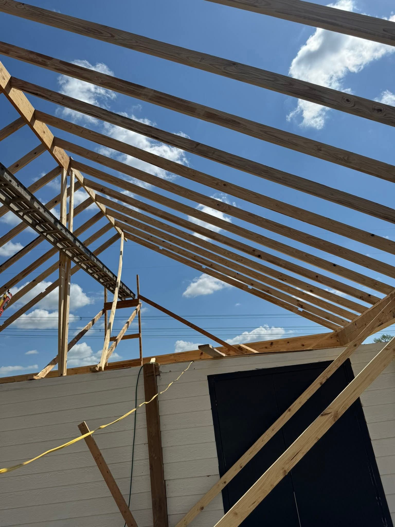 View from inside structure showing exposed wooden roof rafters being installed