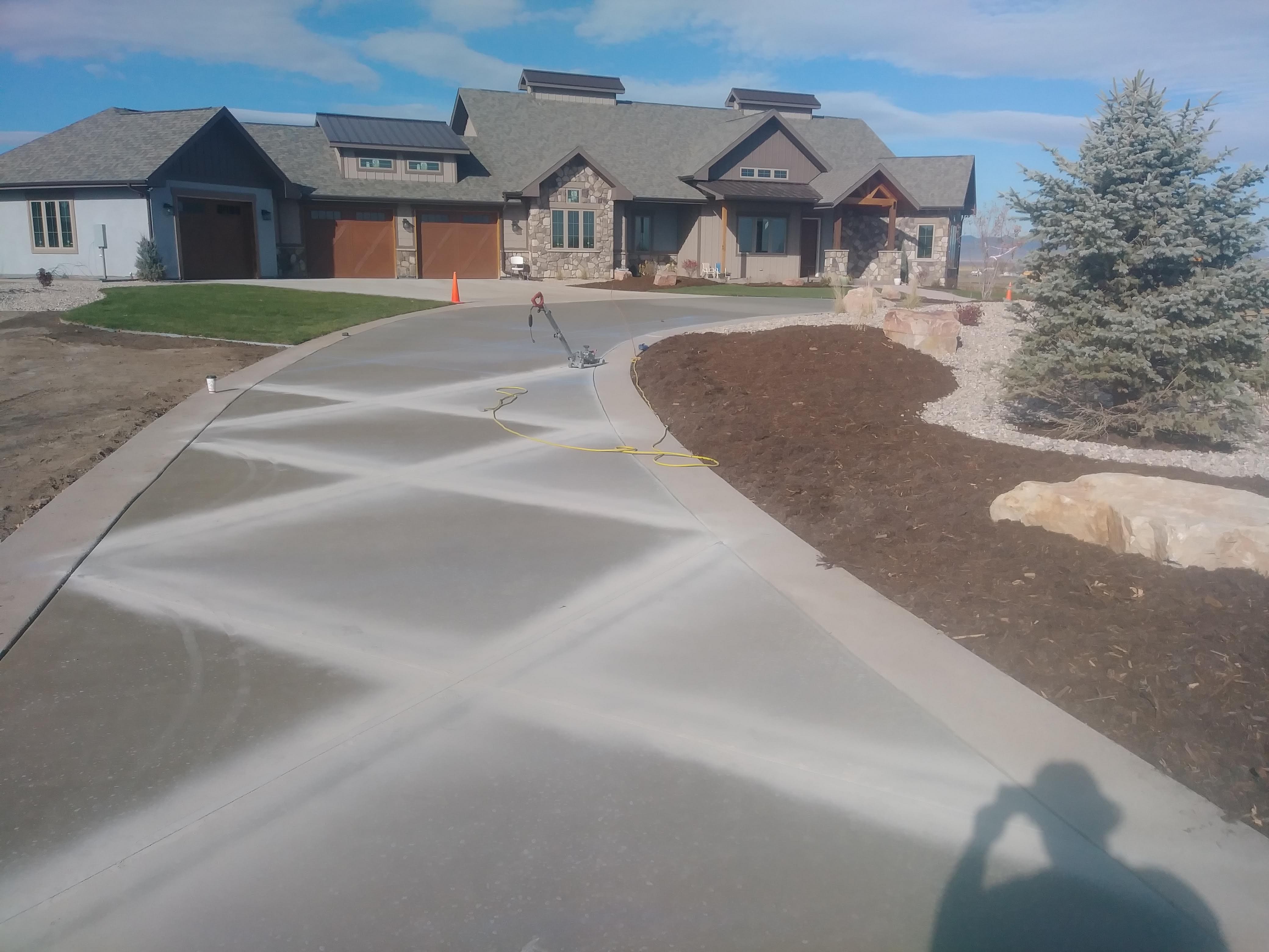 Large residential concrete driveway with a smooth decorative finish and curved layout, complementing the landscaping and exterior of the home.