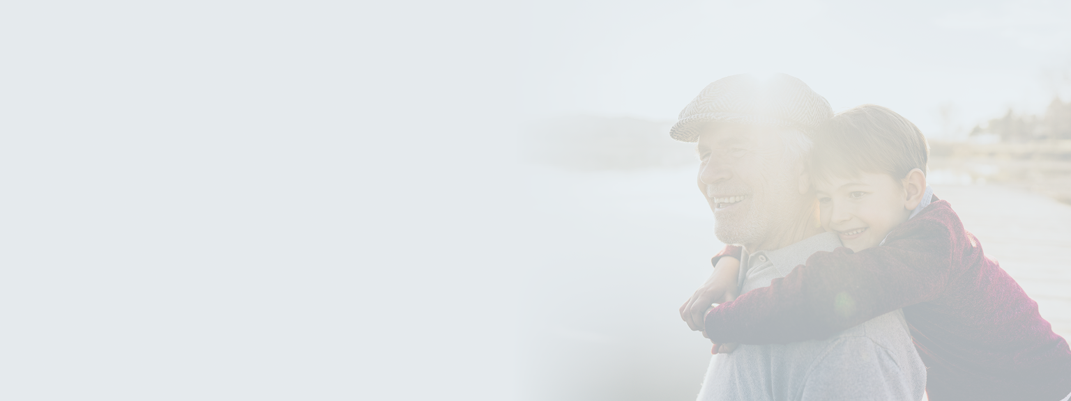 A grandfather smiling while carrying his grandson on his back.
