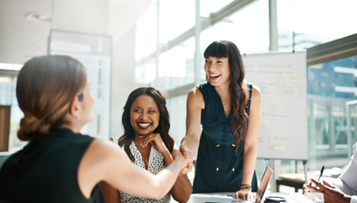 Professionals shaking hands across a boardroom table.