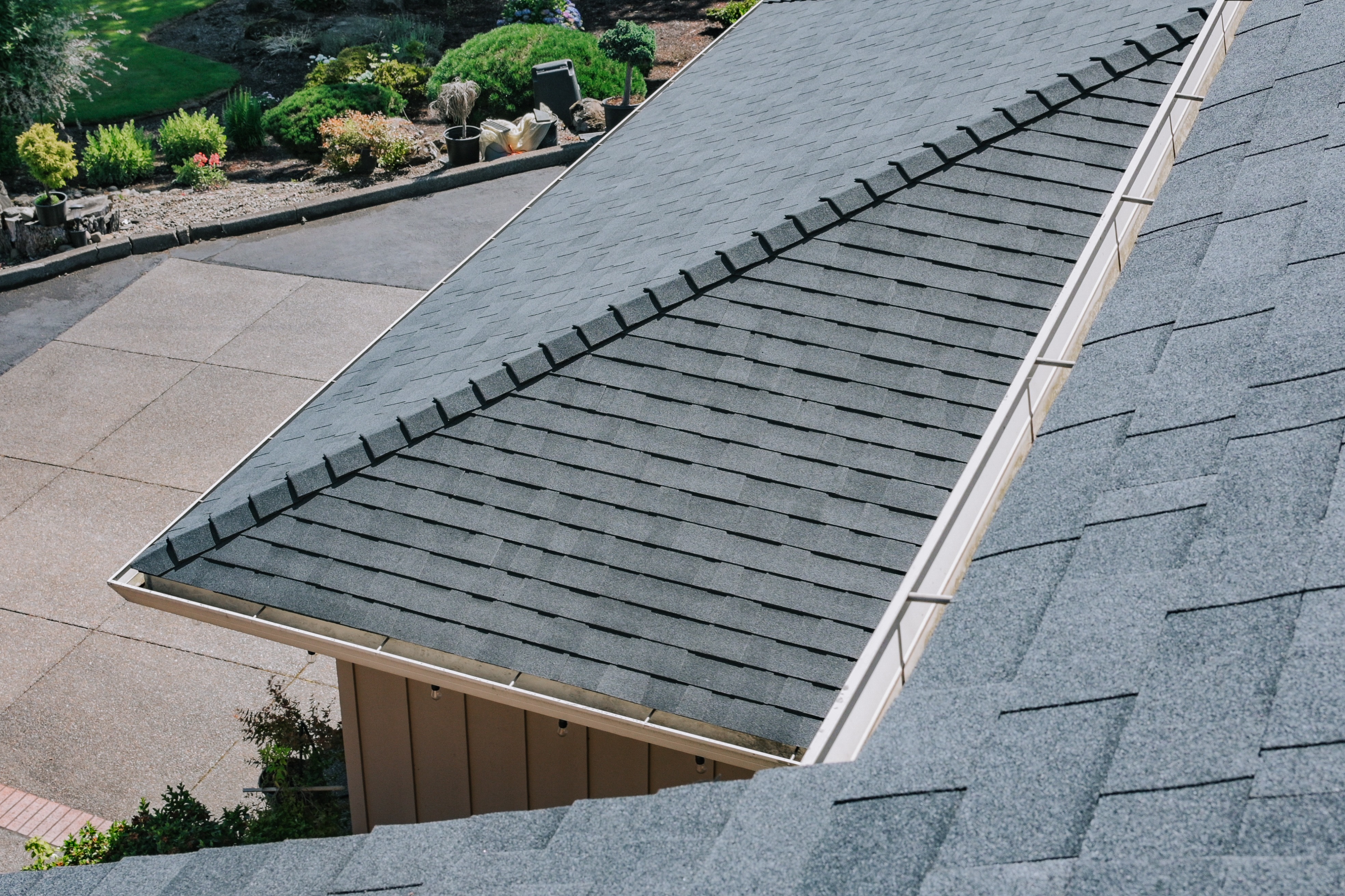 Completed asphalt shingle roof section with ridge-cap shingles installed on hip and a clean finished 