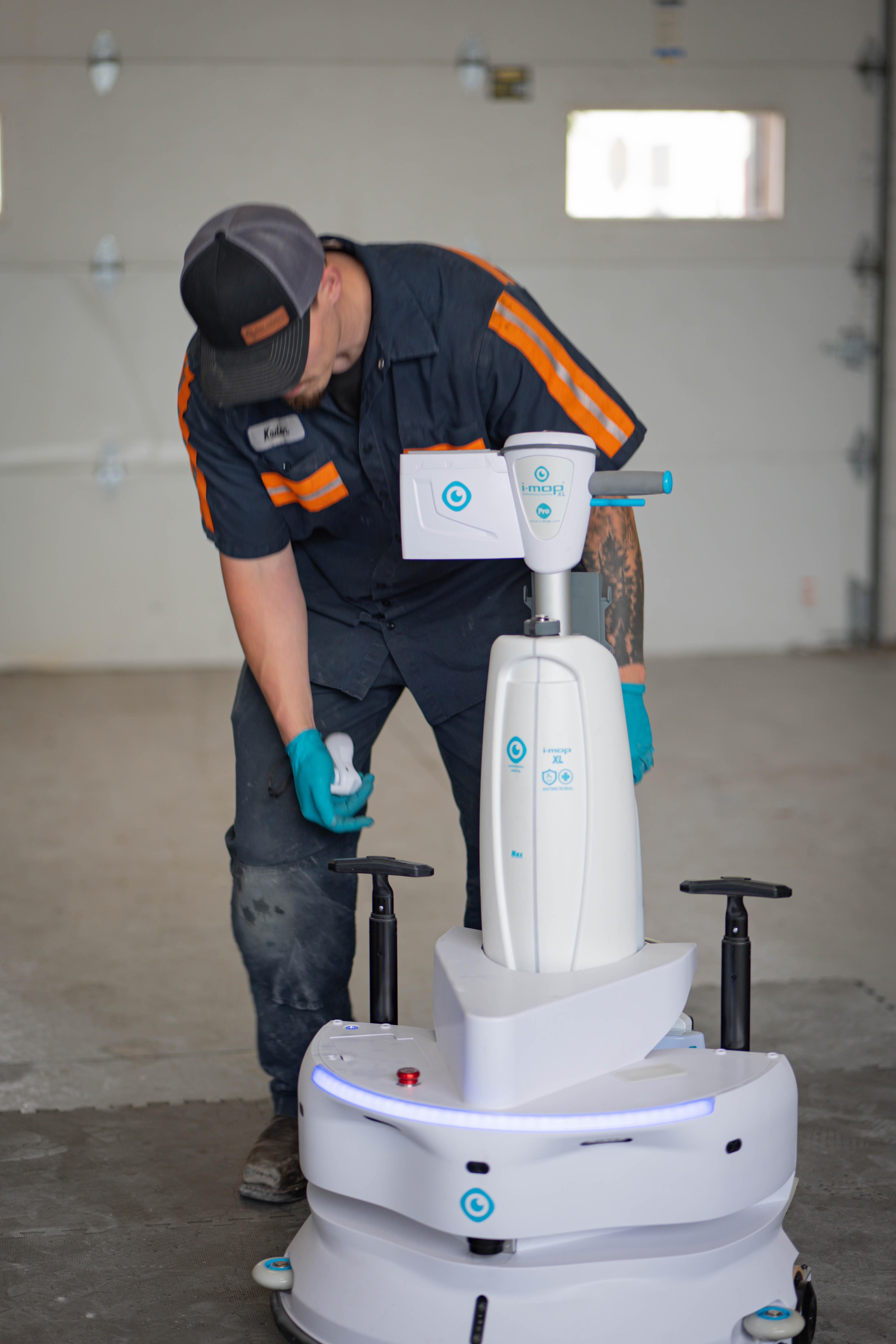 A certified WaySolutions technician carefully inspects the internal housing and components of a teal walk-behind commercial floor scrubber. Serving facilities in Layton, Utah, our experts accurately diagnose mechanical issues and supply genuine OEM replacement parts to ensure your industrial cleaning equipment operates flawlessly.