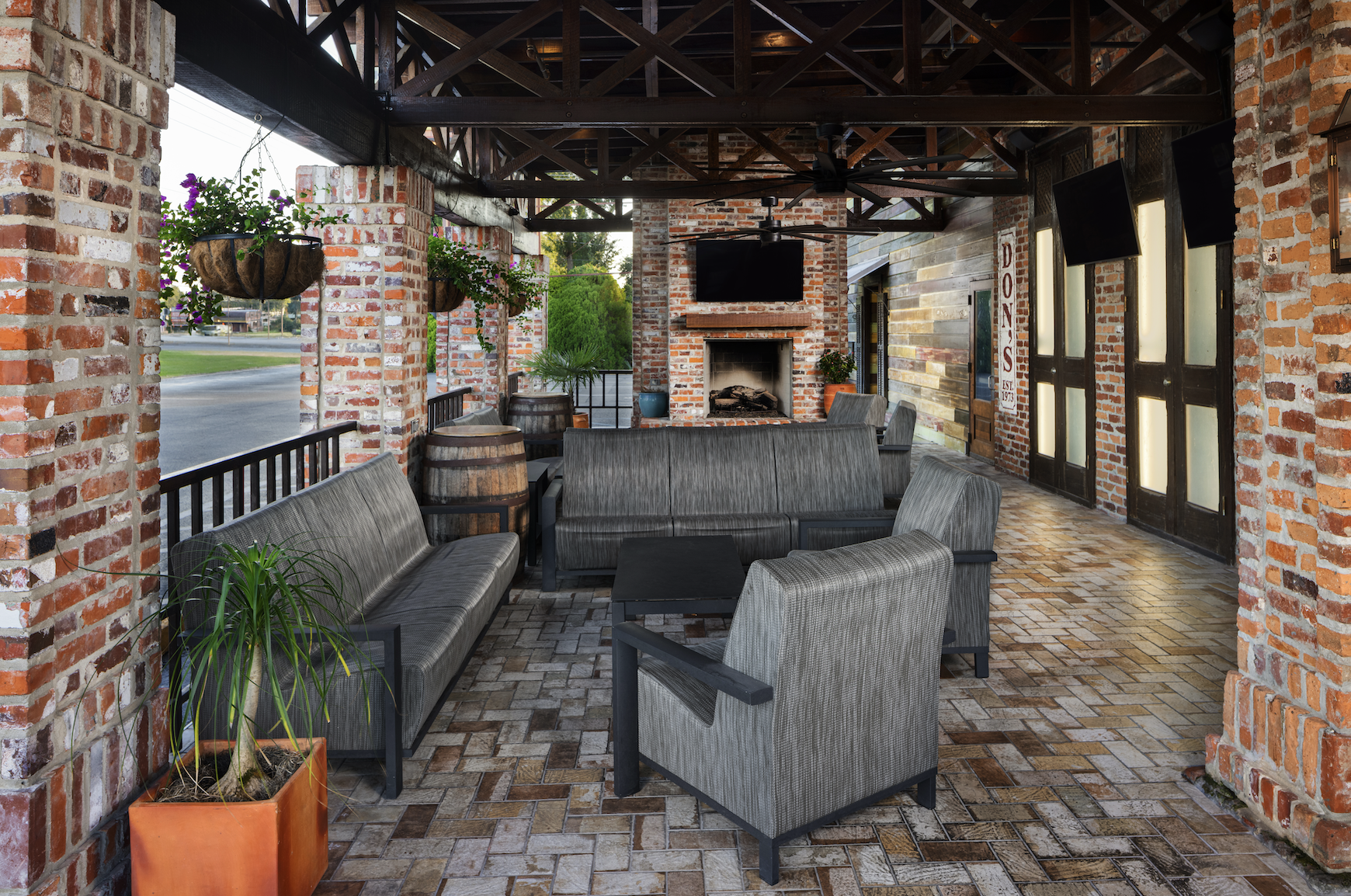 An inviting covered patio at our Lafayette location, centered on a brick fireplace with comfortable  