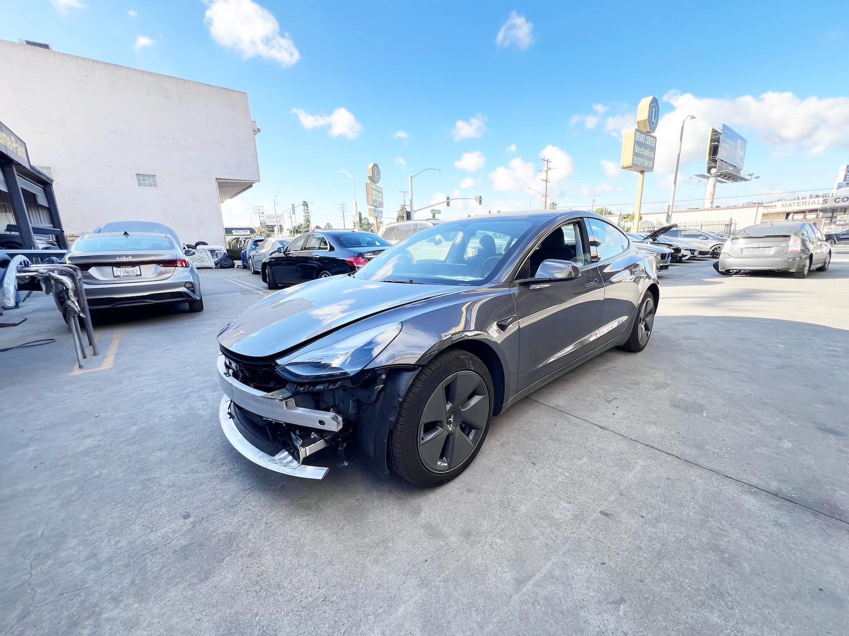 Detailed photo of Tesla Model 3 waiting at auto body shop parking lot for collision repair