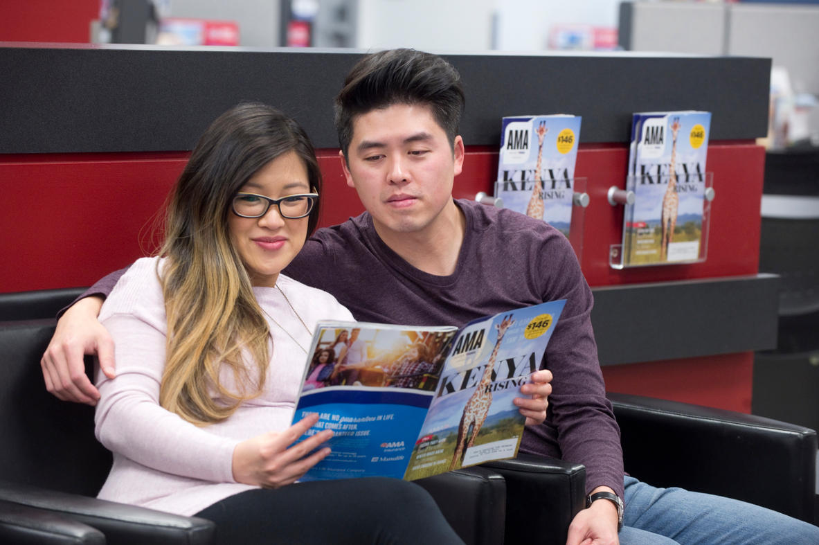 Members in waiting area browse travel magazine AMA Travel Calgary (403)240-5350