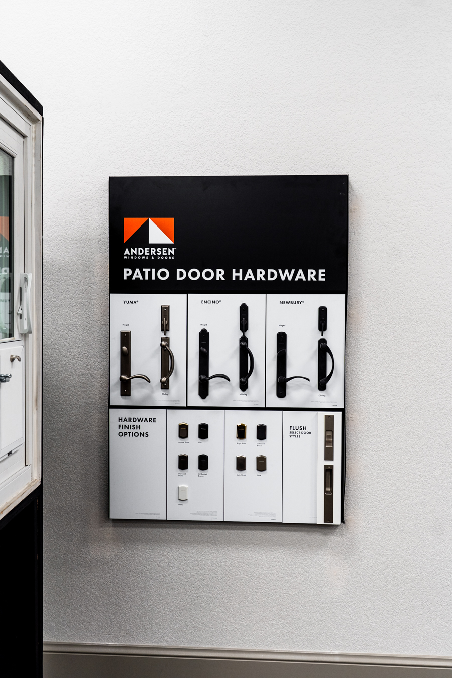 Builders FirstSource display of Andersen patio door hardware options on a wall, showcasing various handle styles and finishes.