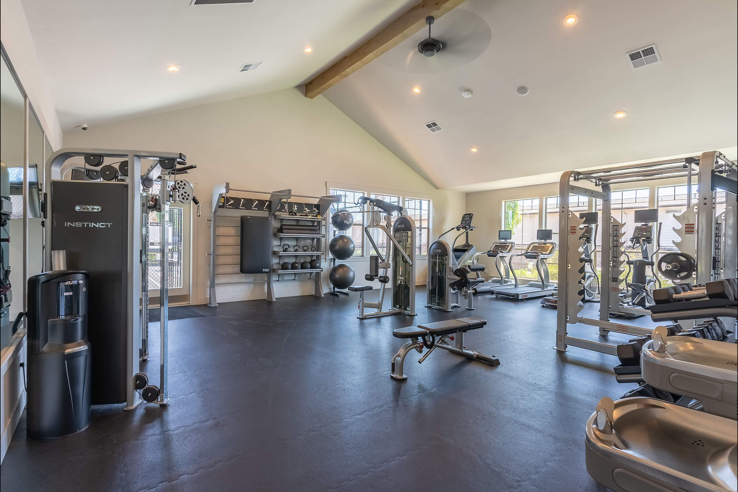 A spacious gym with various exercise equipment and a bench.