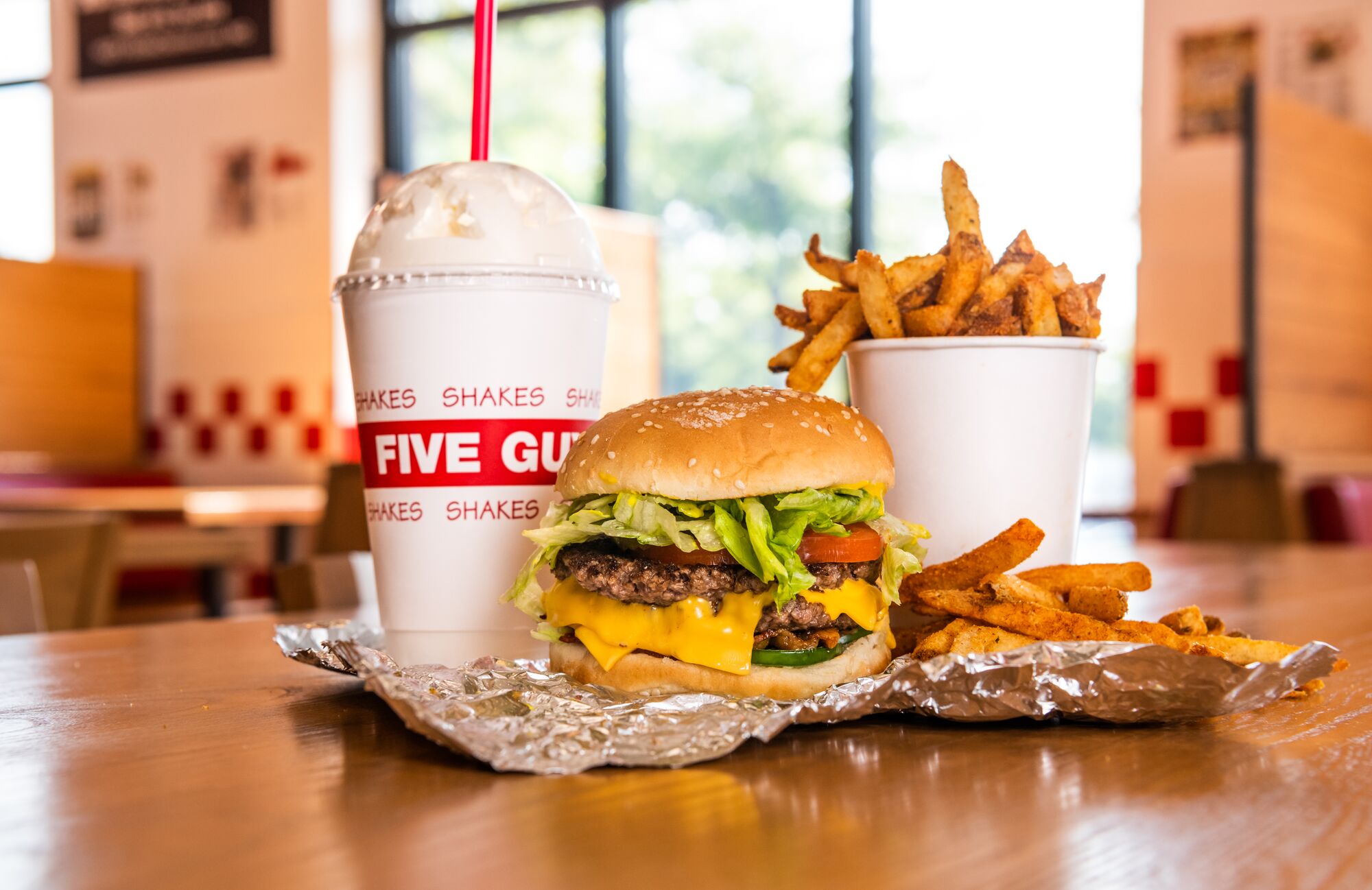 A Five Guys cheeseburger, milkshake and regular order of fries sits on a table inside a Five Guys re Five Guys Ottawa (613)562-8119