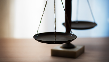 Close-up of balancing scales on a wooden table.