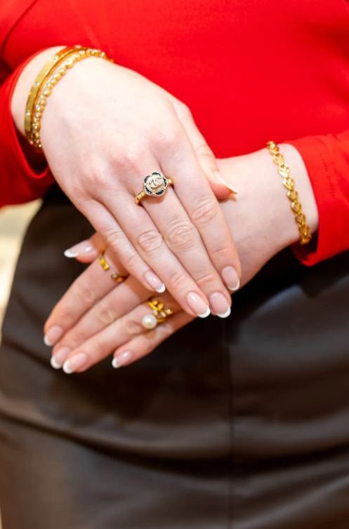 Gold-tone bracelets, a floral statement ring and pearl-accented rings complement a bright red outfit at Eliana Curated. Discover stylish jewelry for everyday elegance in Old Town Alexandria, Virginia.
