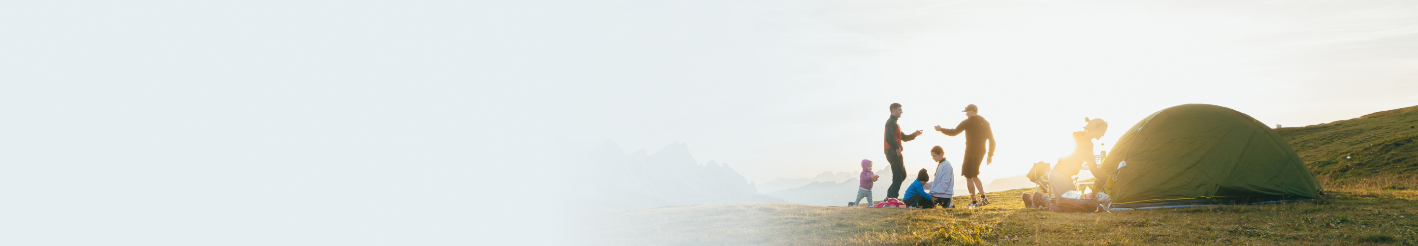 Two young families setting up camp together on the side of a mountain.