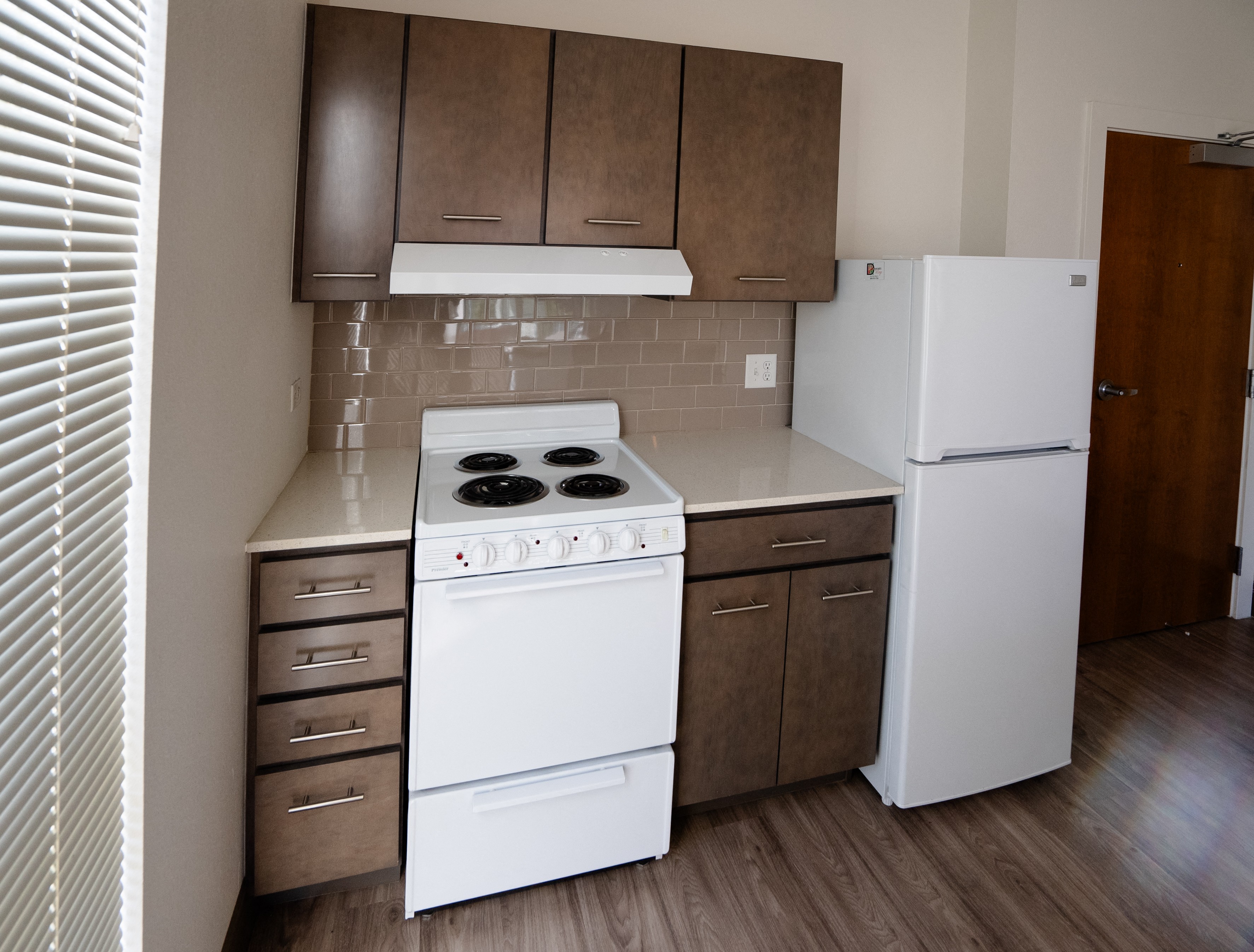 A white stove and refrigerator in a kitchen with brown cabinets.