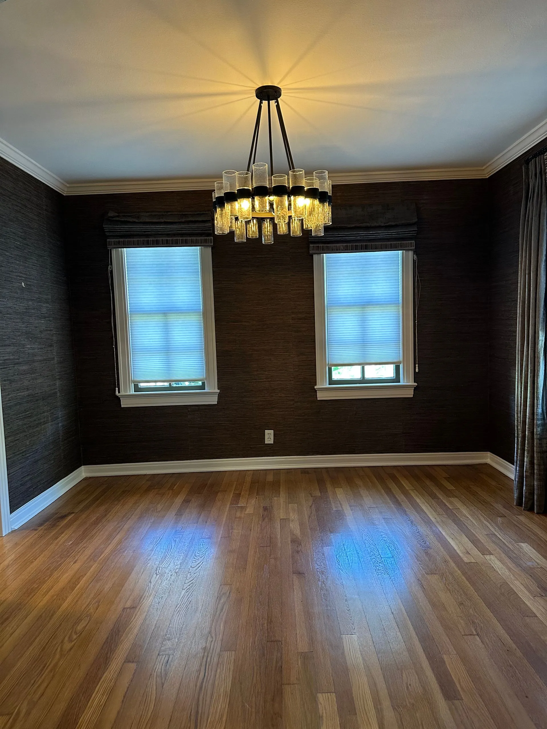 Elegant dining room showcases hardwood flooring, textured accent walls, contemporary chandelier, cus 