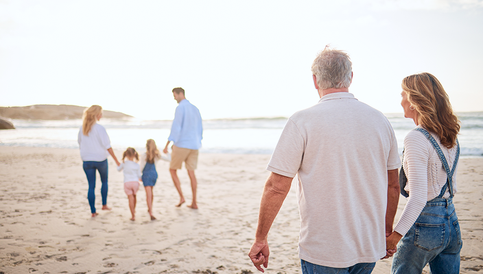 A multigenerational family walking on the beach.