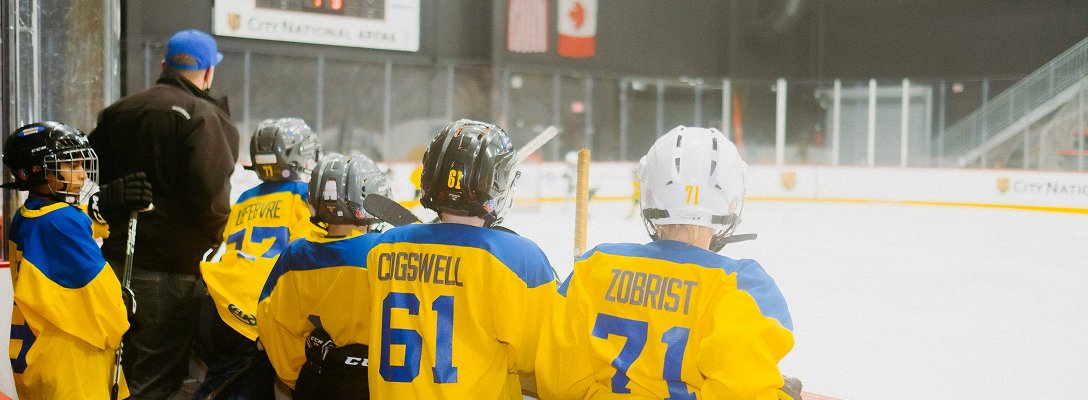 Young minor hockey players cheering on their teammates from the bench.