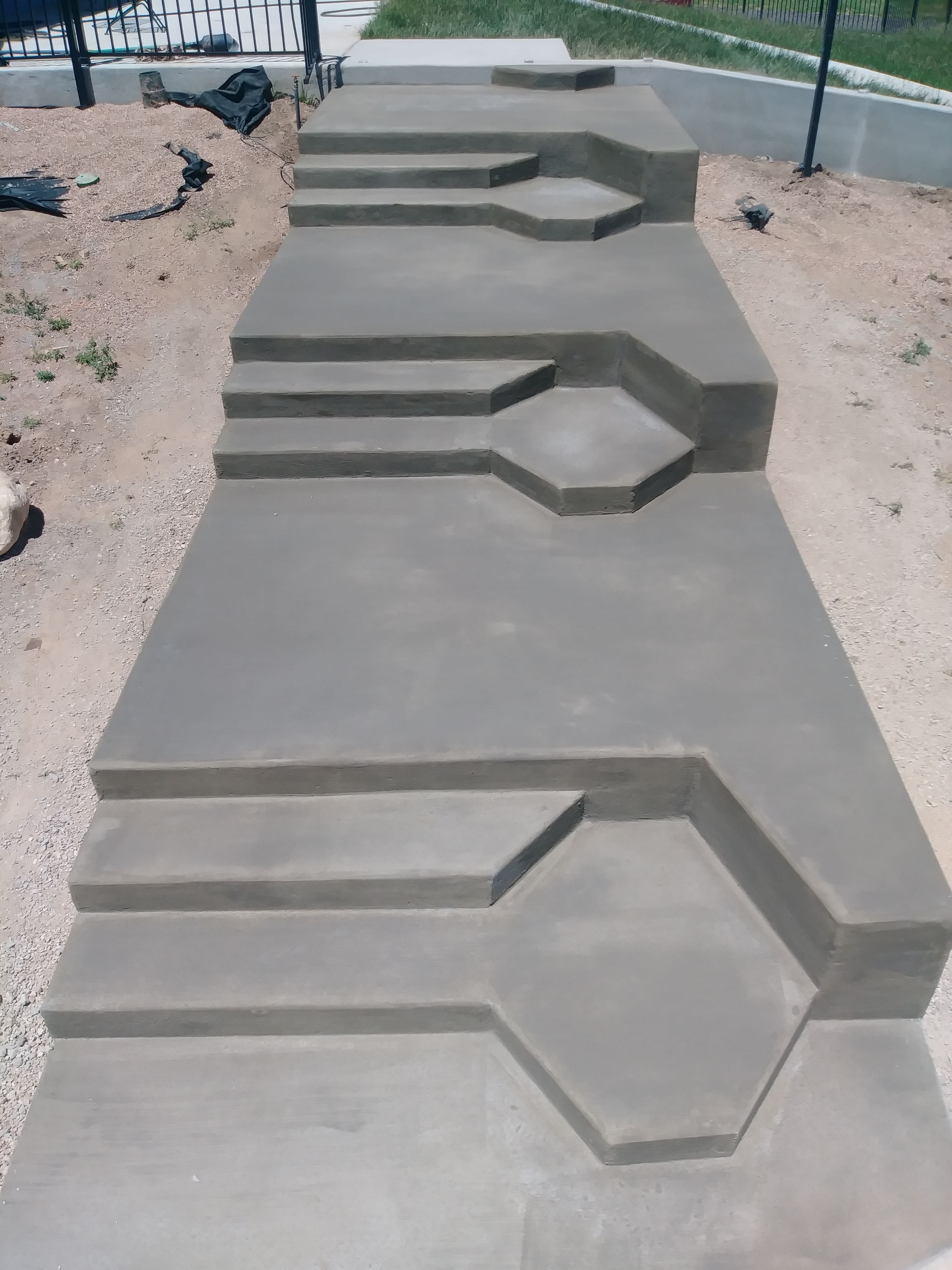 Custom concrete steps and tiered walkway creating a durable, functional transition between different elevations in a residential landscape.