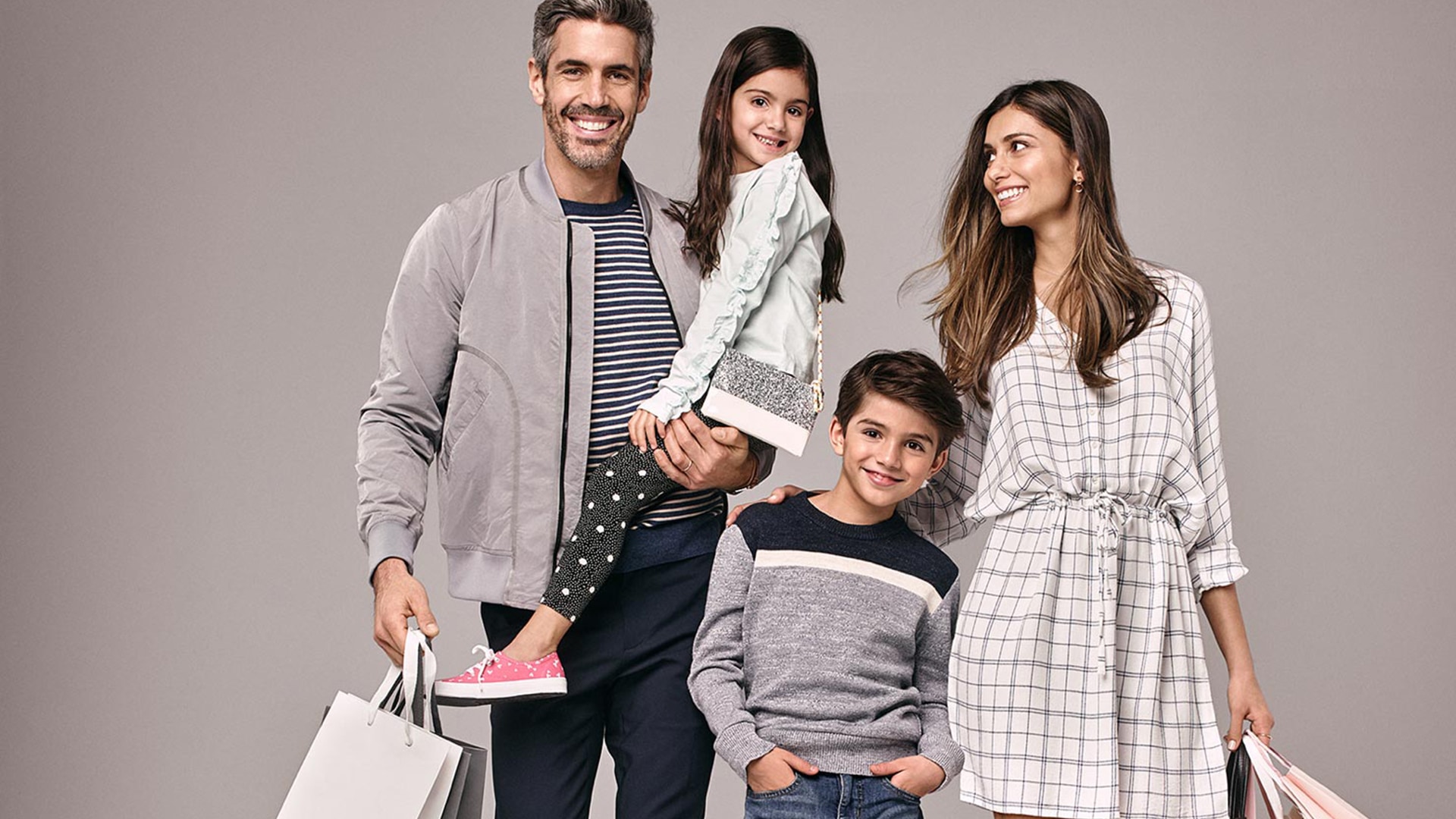 A family of four returning from a trip to a Simon mall with Shopping bags.