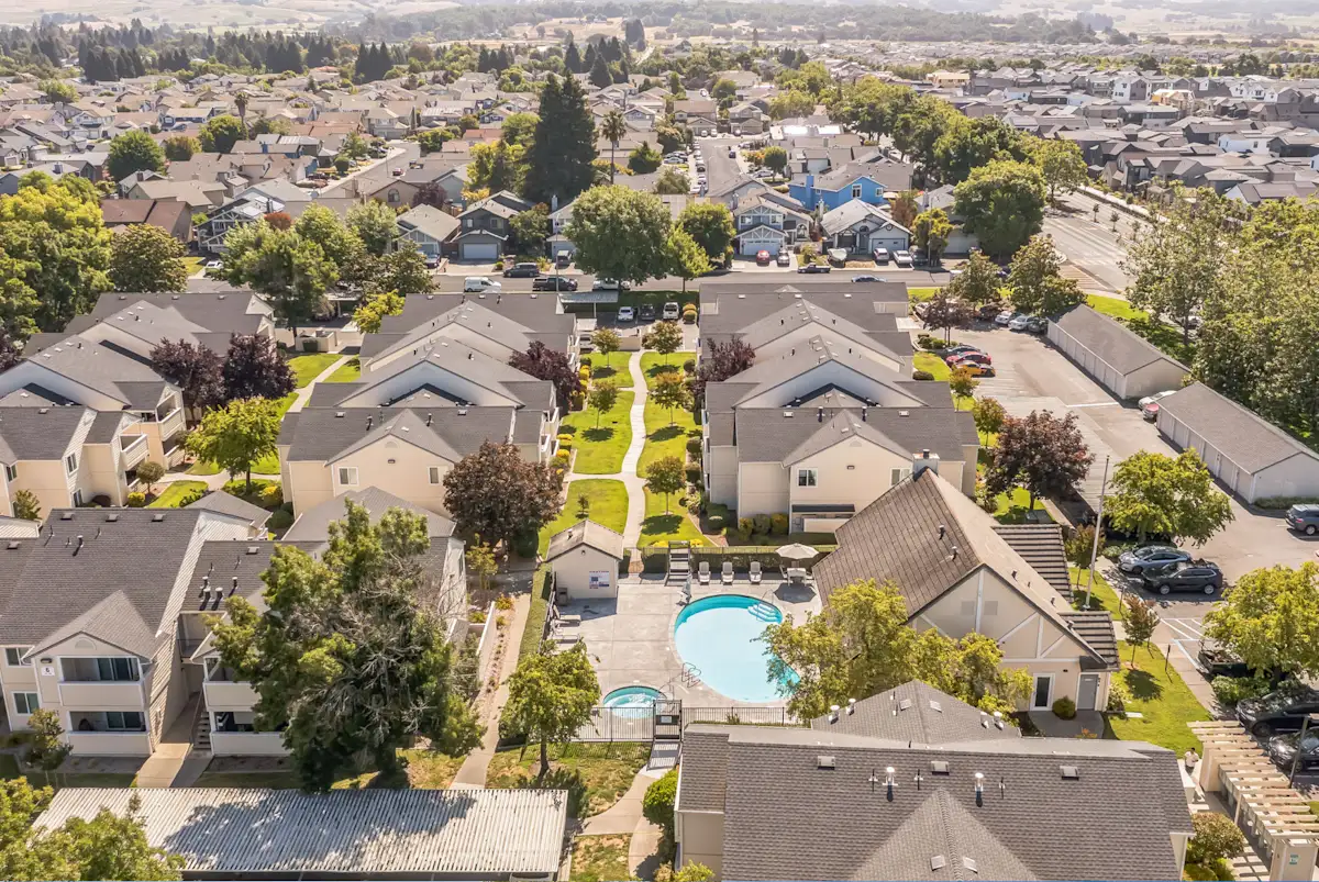 A bird's eye view of a residential area with houses and a swimming pool.