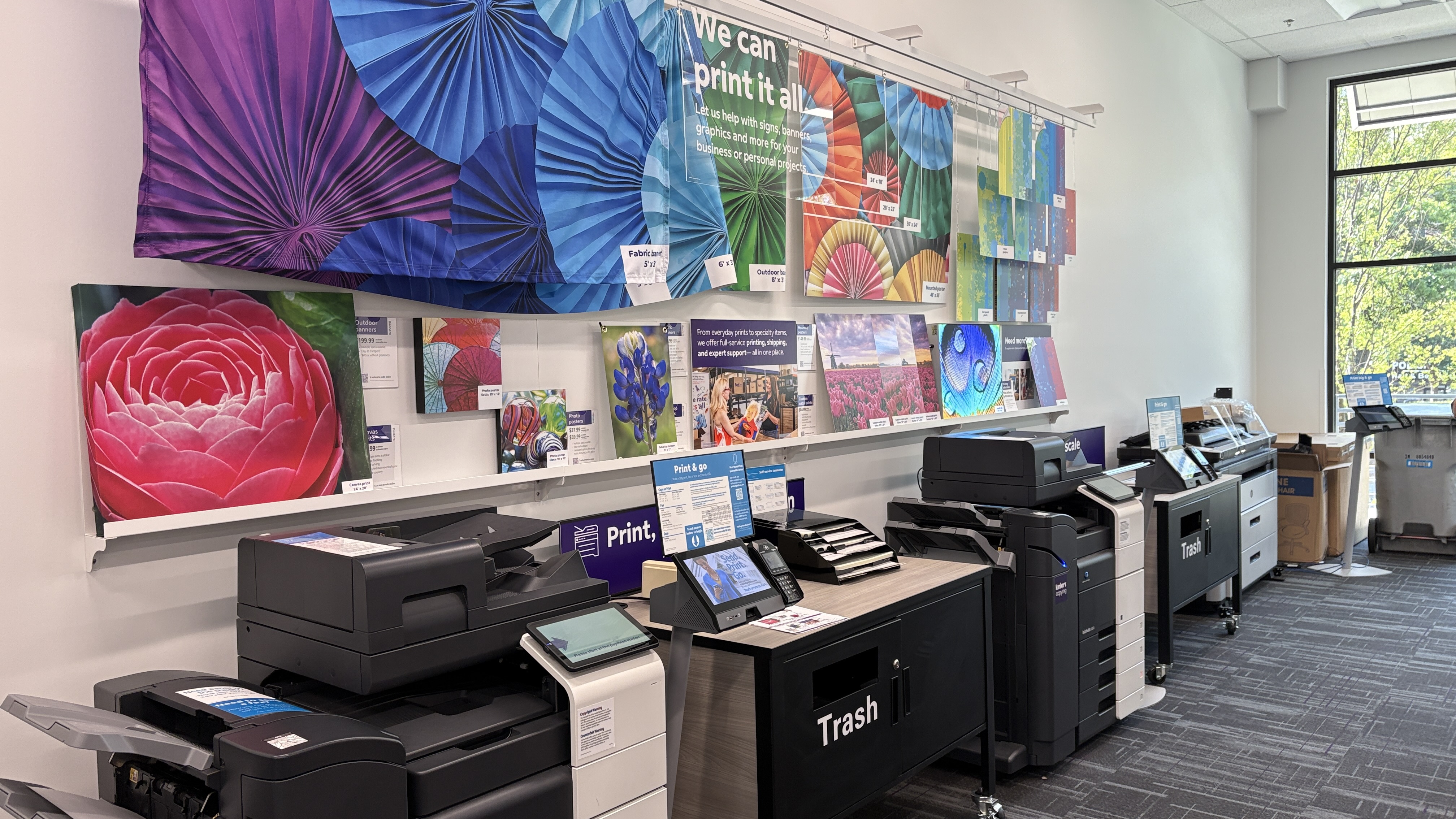 The self-service printing area with Print & Go stations for copies, scanning, and faxing, alongside a display of custom print options.