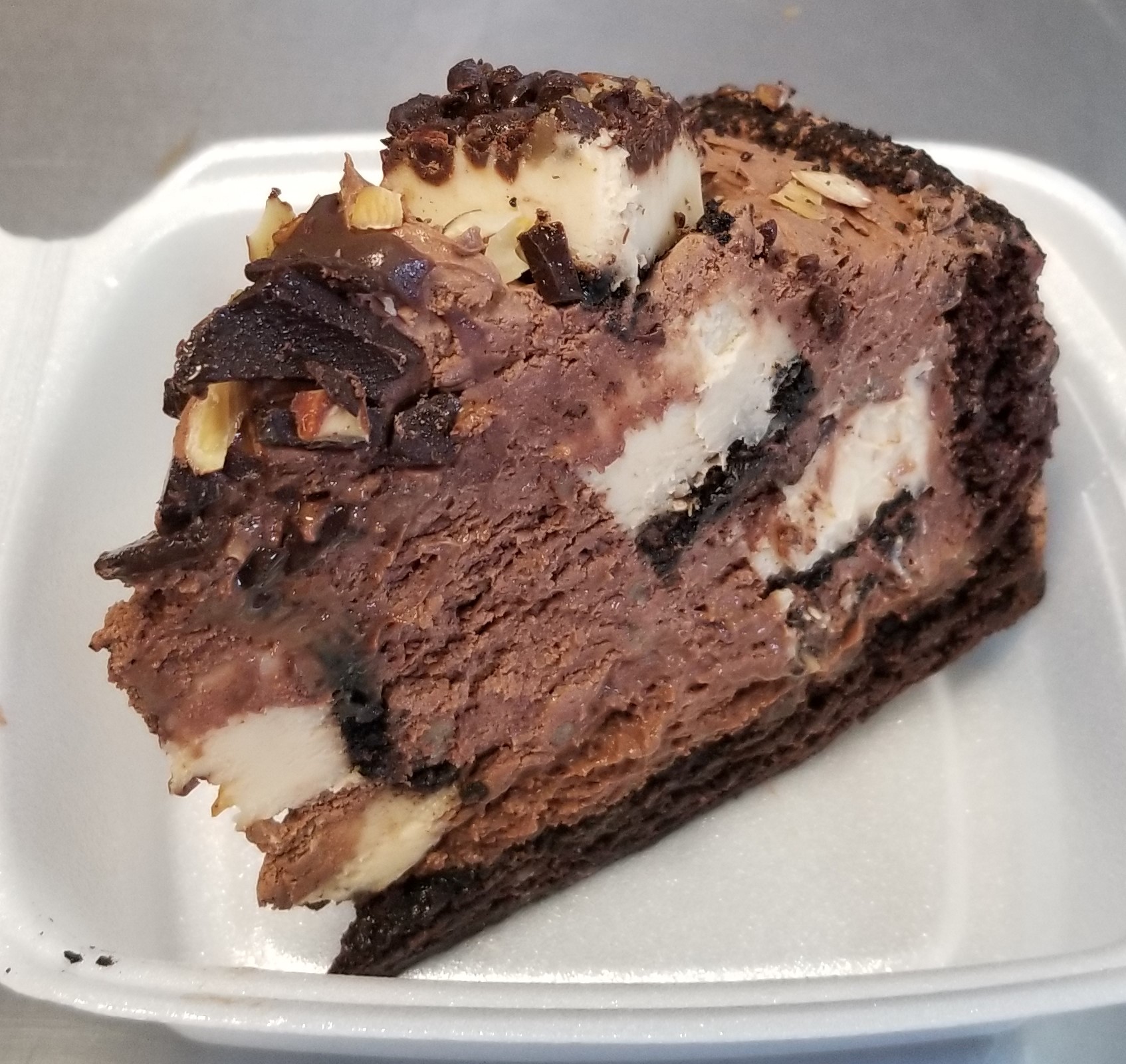 Chocolate Eruption is a loaded triple chocolate cake with huge chunks of Classic New York Cheese cake throughout. Topped with chunks of shaved chocolate, sweet roasted almonds and light caramel drizzle. When  you can't decide between chocolate cake and cheesecake, you have to get both!