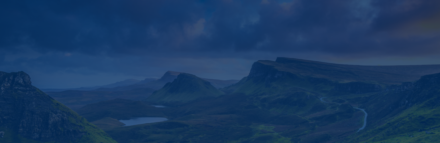 A sweeping landscape of rolling hills under a dramatic cloudy-filled sky at dusk.