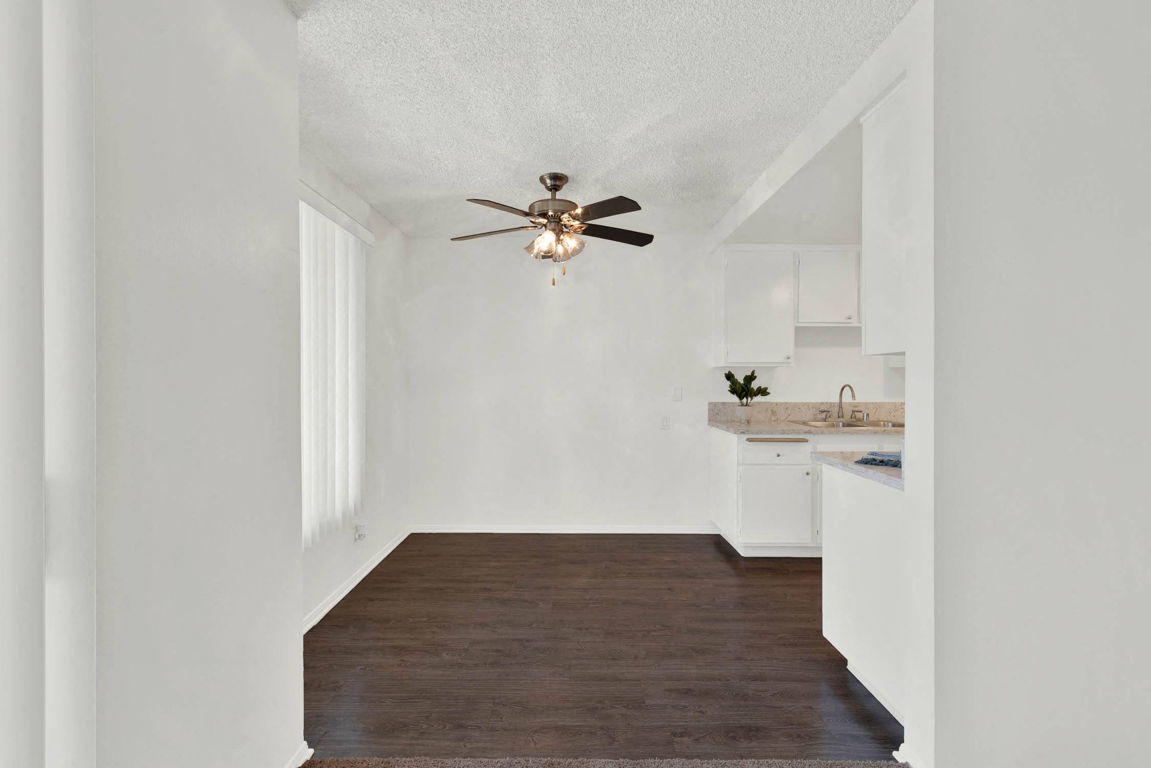 a living room with a ceiling fan and a kitchen