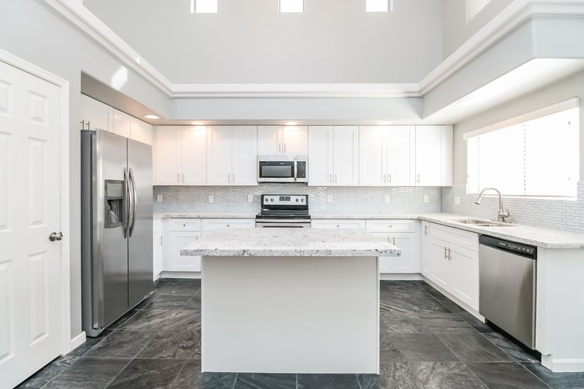 Gorgeous bright kitchen with island, all white cabinetry and stainless-steel appliances at Invitation Homes Phoenix.