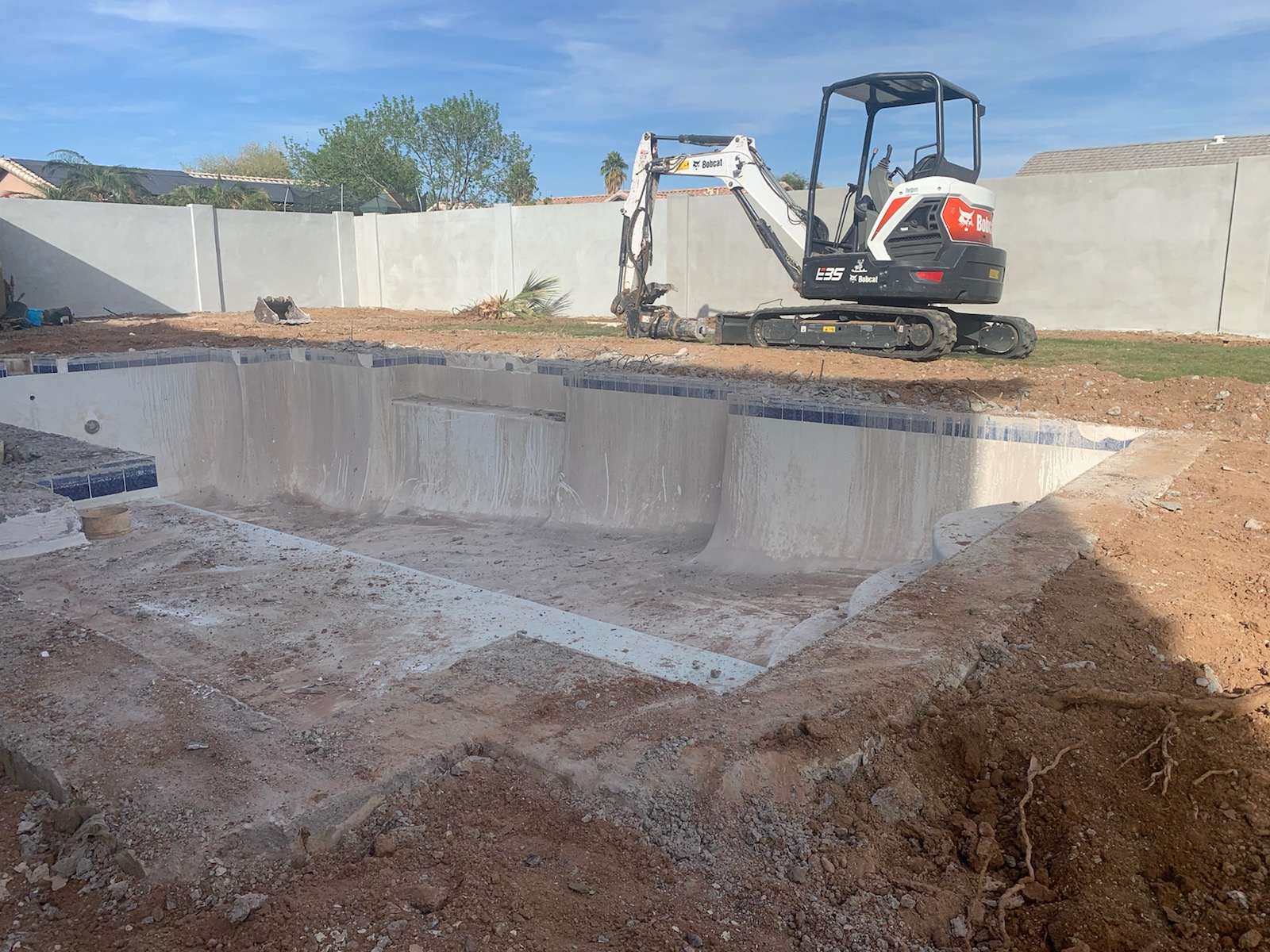 Major pool remodeling work underway with the swimming pool drained and excavation equipment on site. 