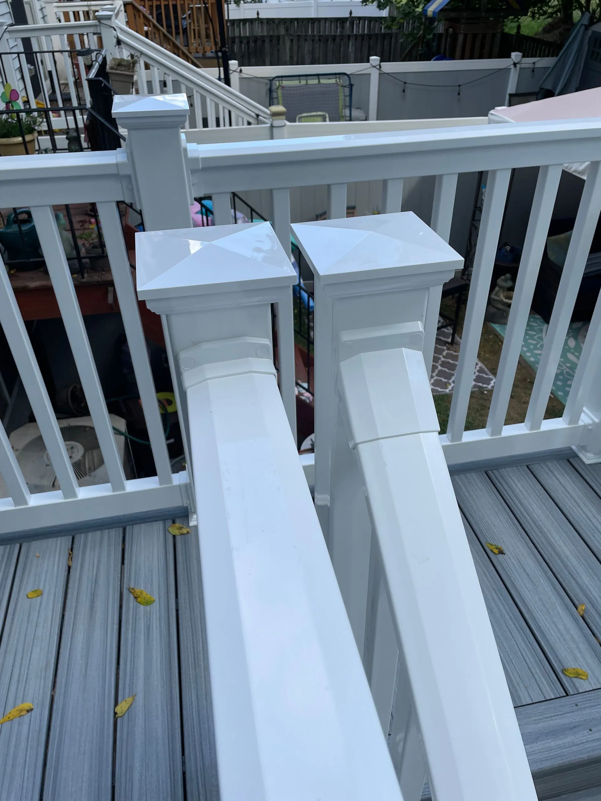 Close-up view of white vinyl deck railings and posts installed on composite decking. The design emphasizes safety, durability, low maintenance, and clean architectural detailing for outdoor spaces.