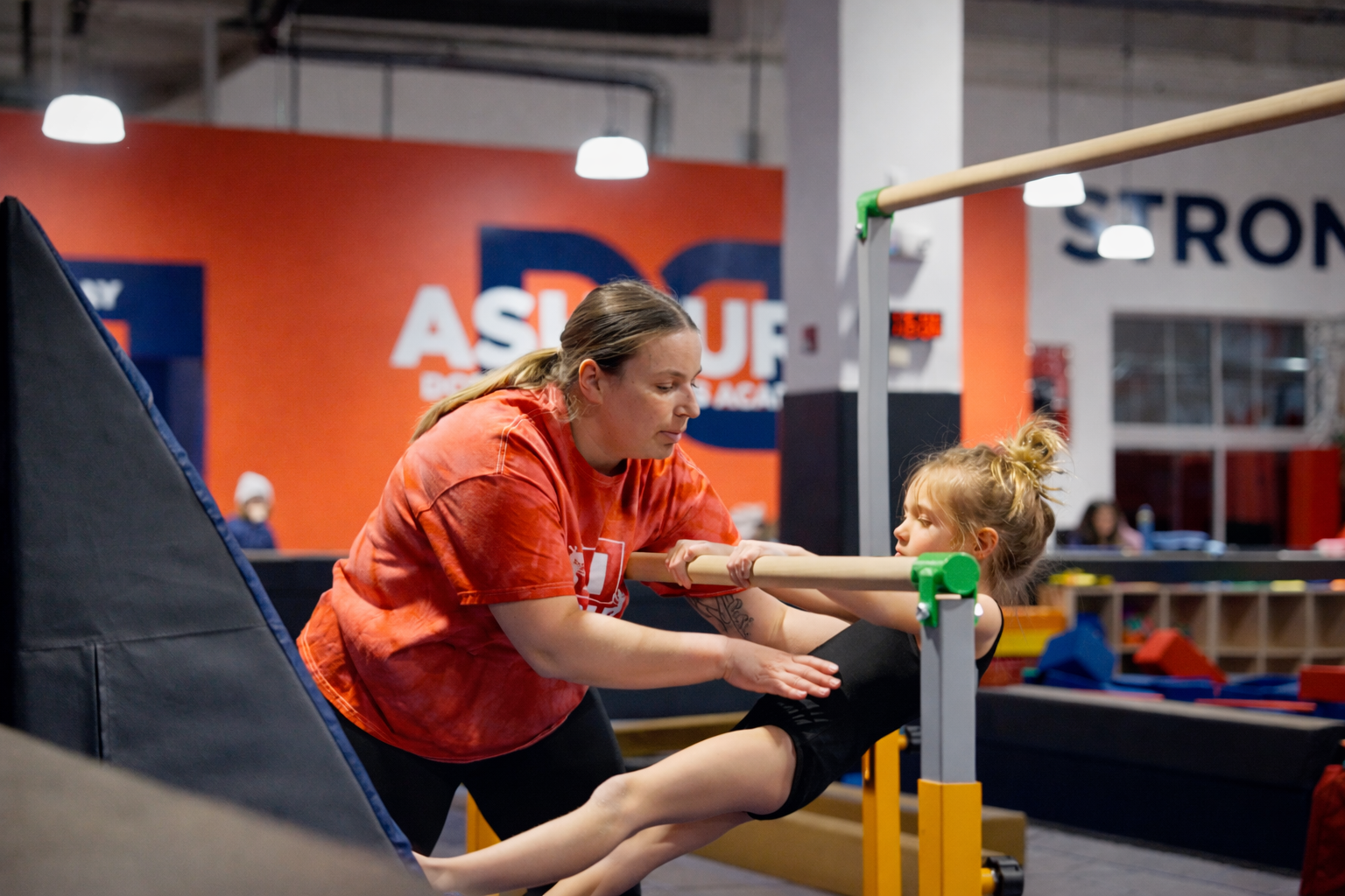 Learning gymnastics moves safely with coach.