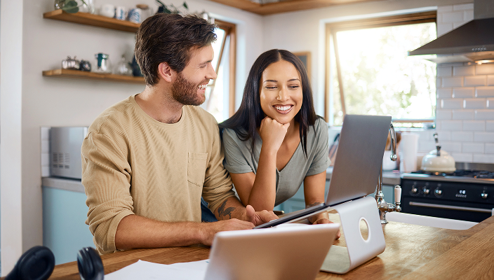 Clients looking over their finances on a laptop in their kitchen.