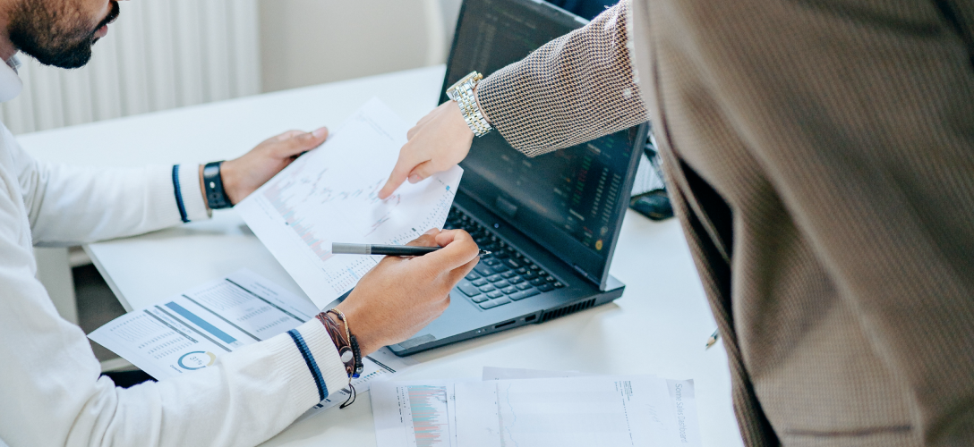 Close-up of two professionals reviewing charts and graphs.