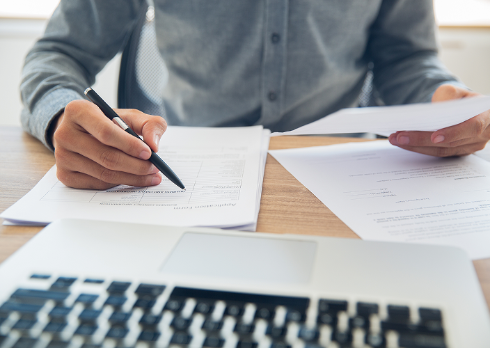 Close-up of a person filling in printed forms.
