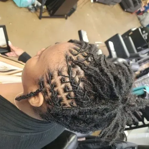 Creative loc repair hairstyle featuring intricate scalp sectioning and restored dreadlocks gathered  