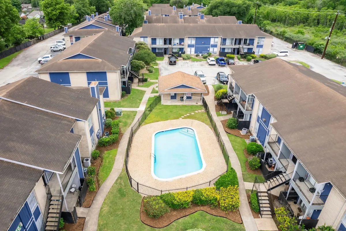 A swimming pool is surrounded by a fence and houses 