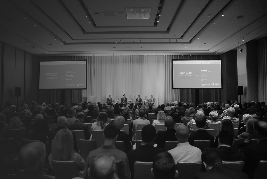 Senior Portfolio Manager, Adam Moody, on stage moderating a panel of wealth management experts in front of a large audience.