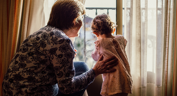 A grandmother and her grandchild looking out the window.