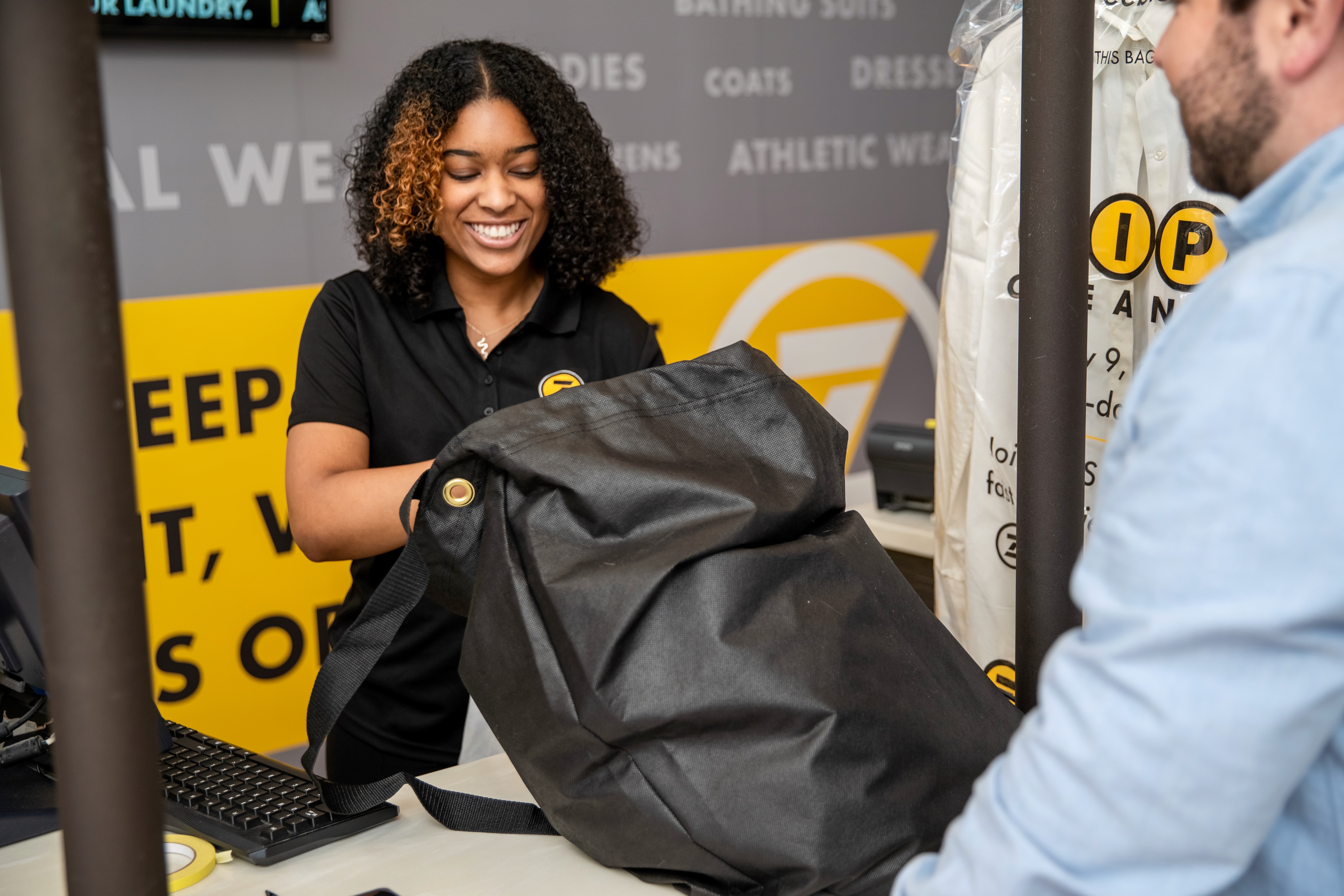 A friendly, professional ZIPS Cleaners team member takes in an order being dropped off by a customer ZIPS Cleaners Baltimore (410)216-5068