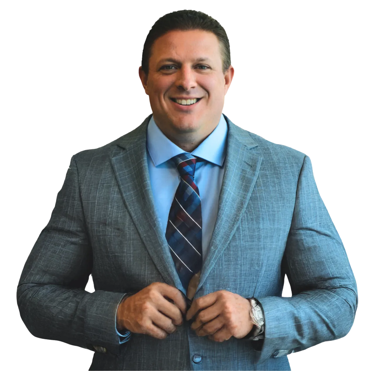 A man in a light blue dress shirt, a striped tie, and a gray pinstripe suit jacket is buttoning his jacket. He is smiling at the camera. The background is white.