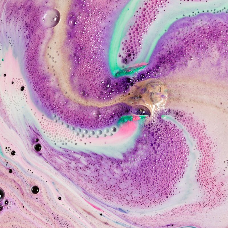 Bath art from our Luxe bath bomb with gorgeous gold, purple and turquoise bubbles.