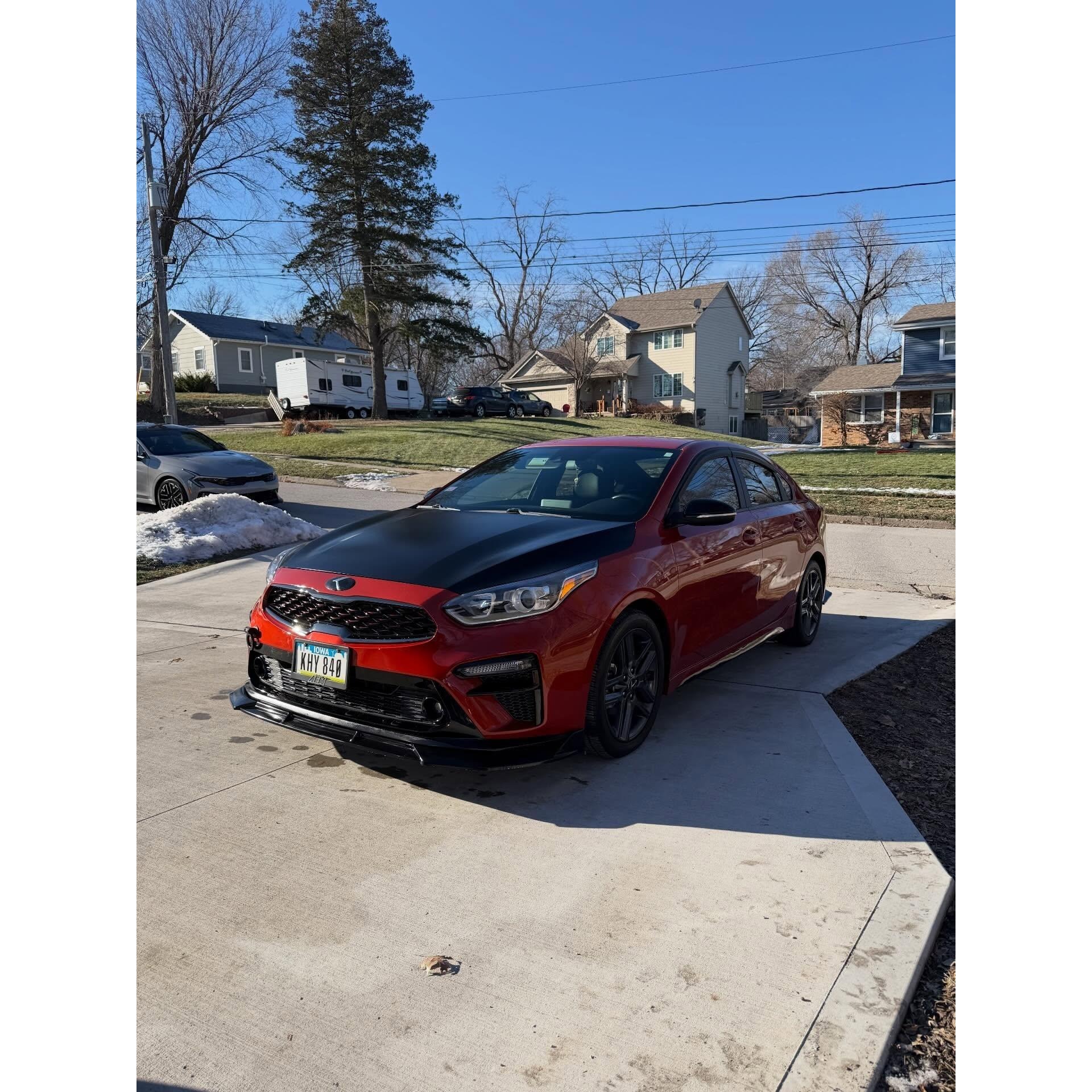 Red sedan parked in a residential driveway, showcasing a clean exterior finish and mobile auto detailing service completed at the customer’s location.