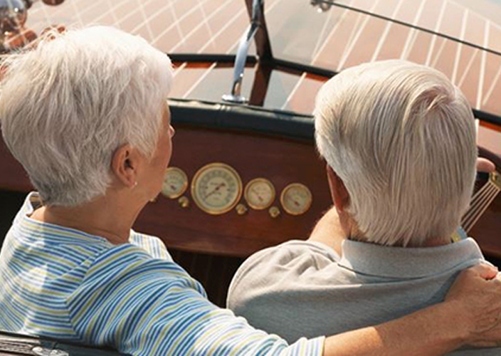 Over-the-shoulder shot of an elderly couple on a private boat.
