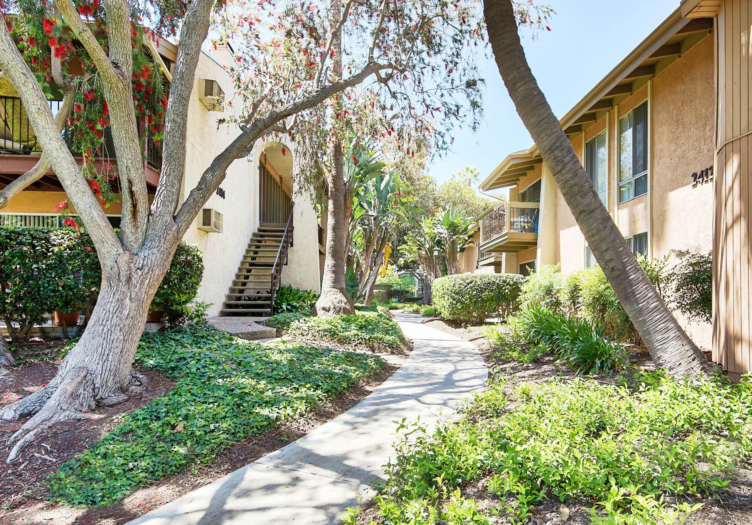 a sidewalk in front of a building with trees