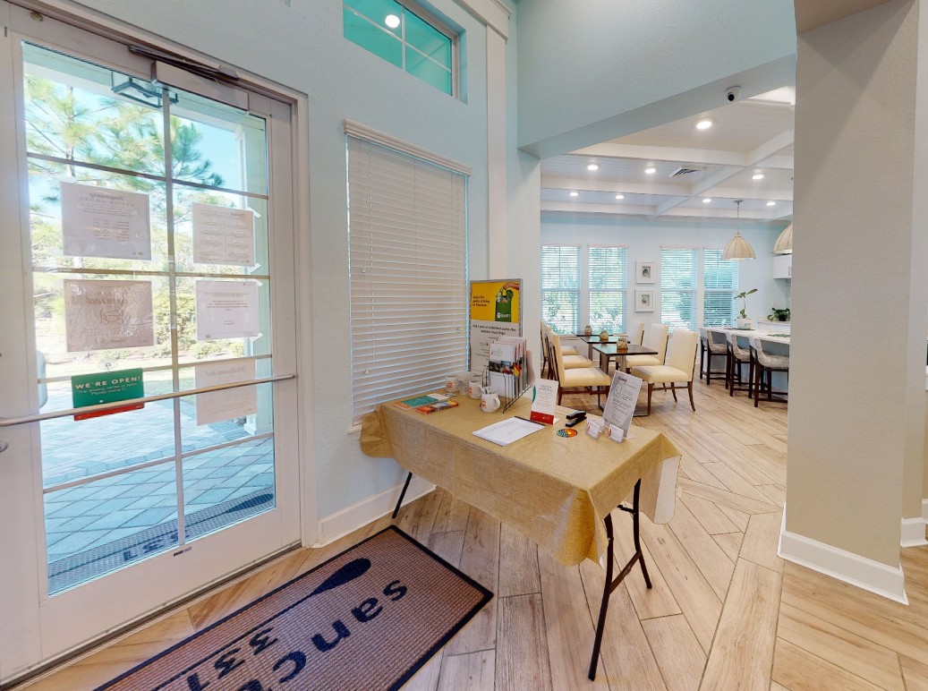 A welcoming clubhouse entry area with an information table and clear view into the community dining space.
