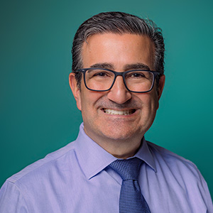 Male family medicine physician smiling in front of green photo background