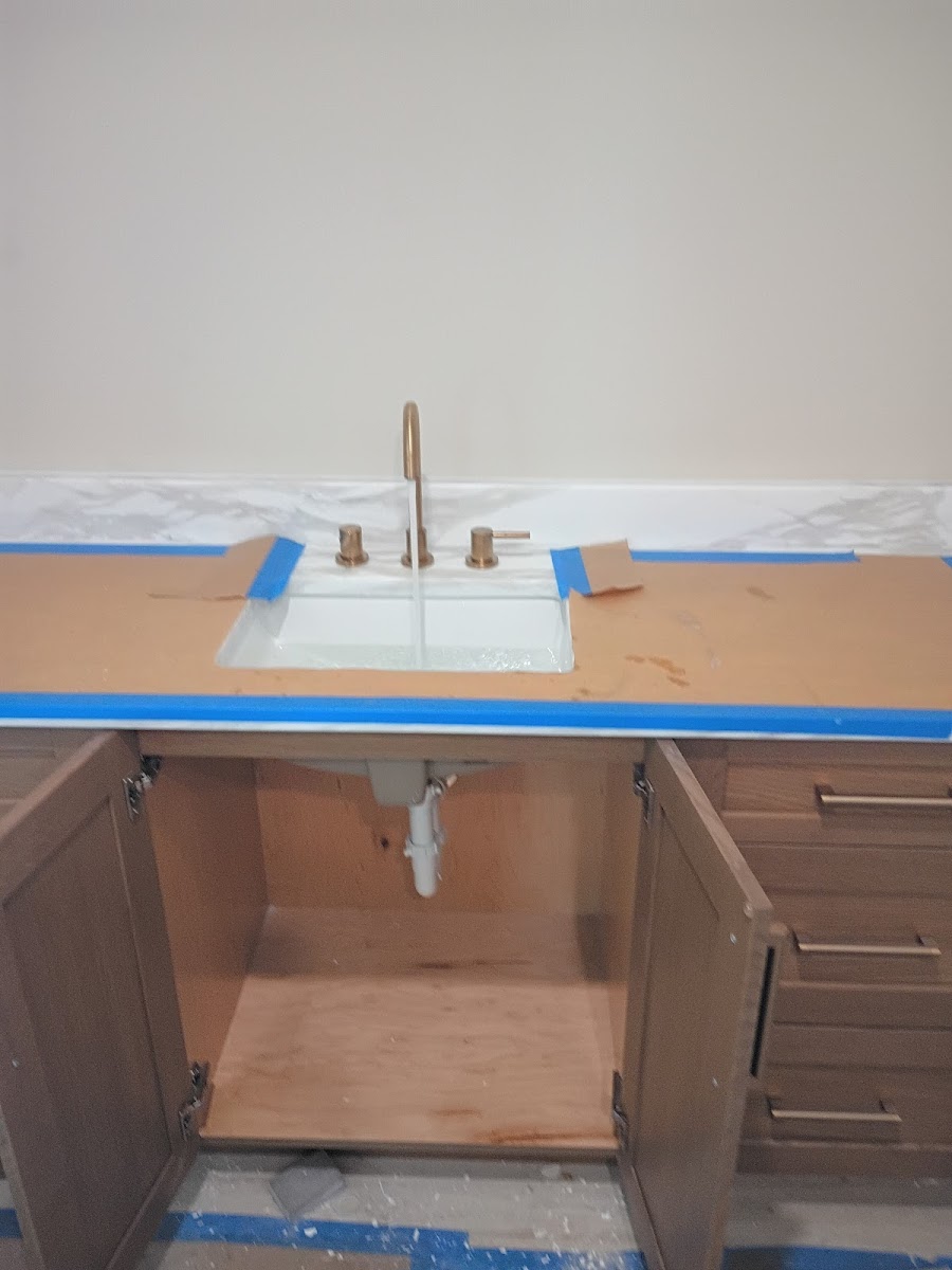 Bathroom vanity cabinet with sink plumbing area prepared for installation, repair, or remodeling work.