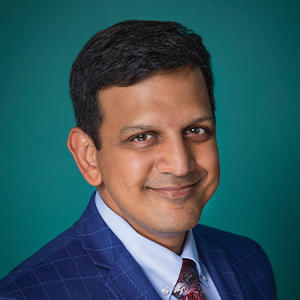 Male doctor smiling with a blue background.