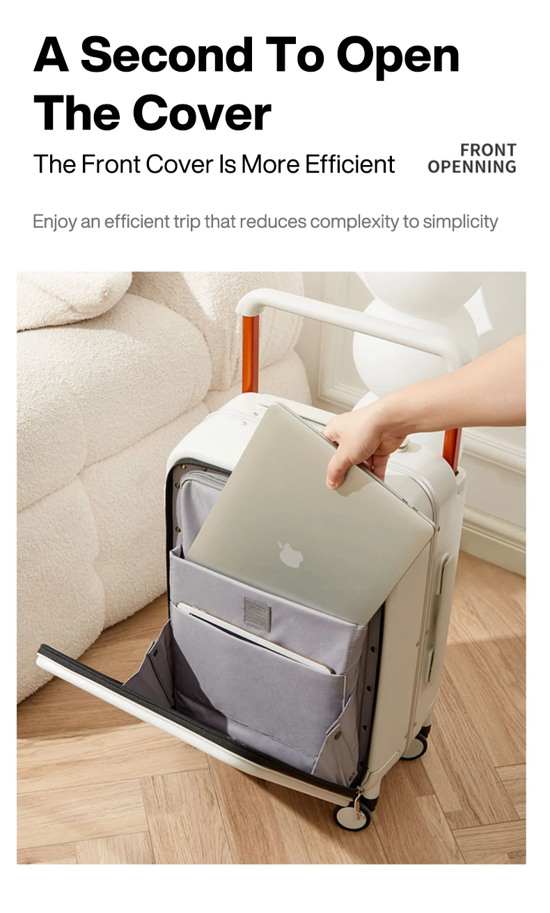 A light-colored suitcase is open with a hand placing a silver laptop with an Apple logo into a padded compartment inside. The suitcase has orange accents on its retractable handle. In the background, a plush, cream-colored armchair and a white sculptural object are visible.