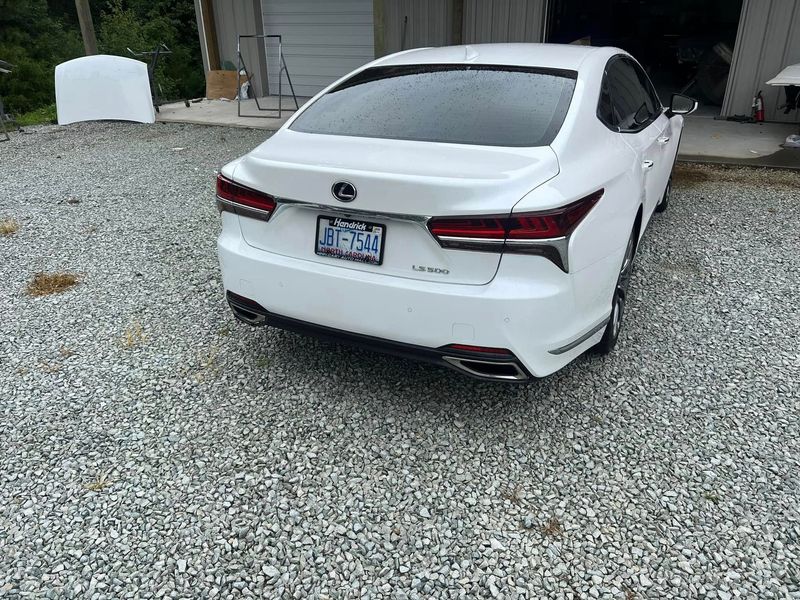 A freshly detailed white Lexus sedan sits outside an auto body facility. The vehicle showcases smooth paint, aligned body panels, and a professional refinishing result after service.