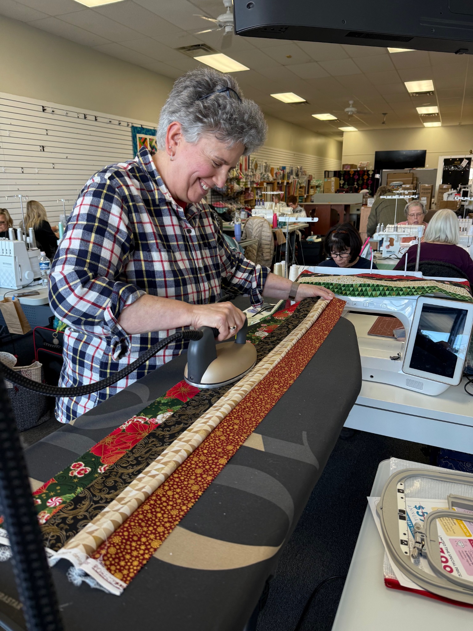 A quilter carefully presses fabric strips during a Decorative Stitch class, learning essential pressing and finishing techniques that help create precise, professional-looking quilting projects.
